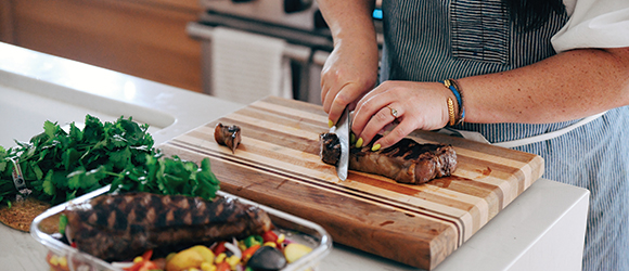 a chef using a knife to chop a steak on a chopping board 