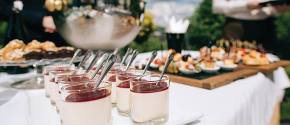finger and dessert food catered and prepared outdoors on a white table cloth 